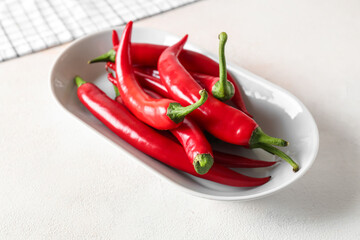 Plate of fresh chili peppers on light background