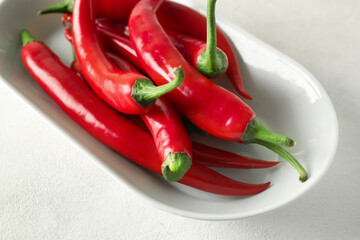 Plate of fresh chili peppers on light background, closeup