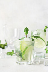 Glass of tasty mojito on light background