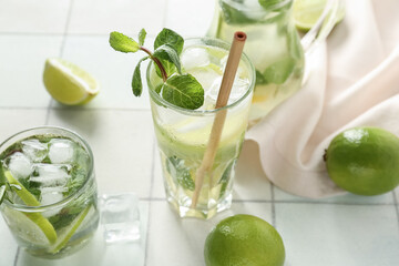 Glasses of tasty mojito on light tile background