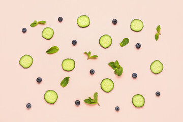 Slices of cucumber with blueberry and mint on pink background