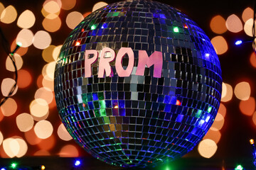 Word PROM with disco ball on dark table against blurred lights