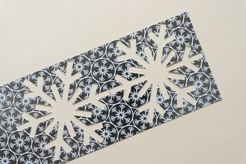 scrapbook paper stencil with snowflake cutouts on blank paper