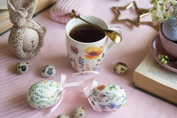 A cup of hot coffee on a festive Easter table with colored eggs.
