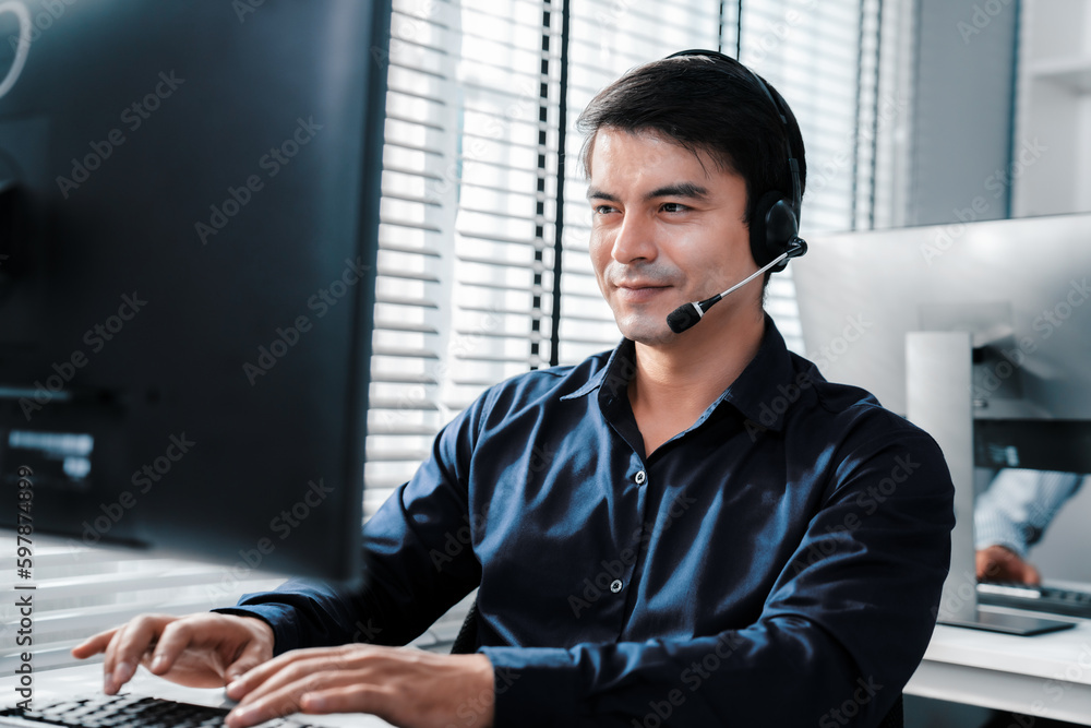 Aufkleber young competent asian male call center agent working at his computer while simultaneously speaking w