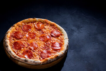 Pizza with tomato sauce, mozzarella, salami on black background. View from above, copy space