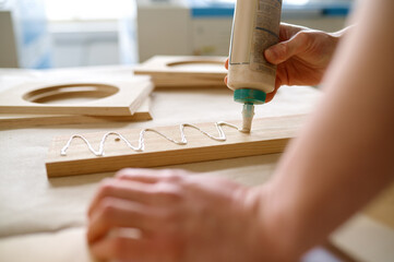 Closeup carpenter applying glue to board wooden timbers - obrazy, fototapety, plakaty