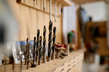 Naklejka na ściany i meble Closeup selective focus on drill bit set at professional carpentry workshop