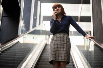 Portrait of a young woman talking on the phone on mobile stairs