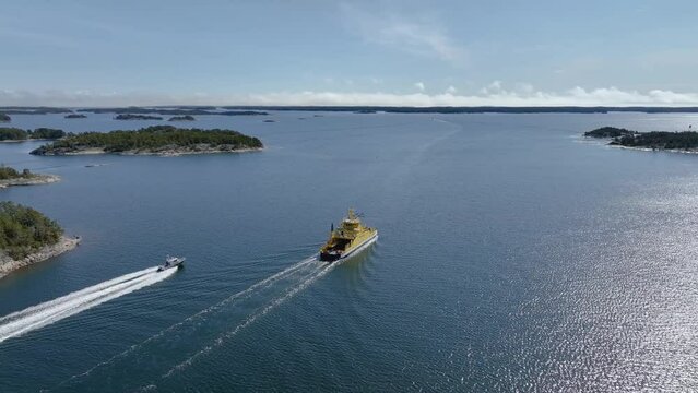 Aerial view of a boat speeding past a vehicle ferry in the archipelago of south-west Finland