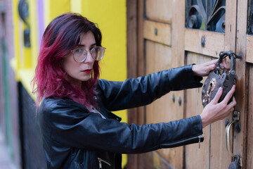 Colombian woman walks through the city and stops to knock on a wooden door