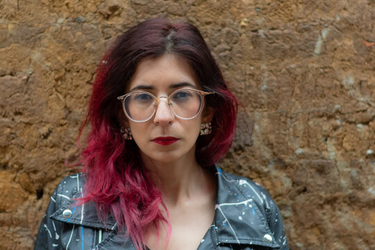 Una mujer de cabello rojo con gafasen un muro 