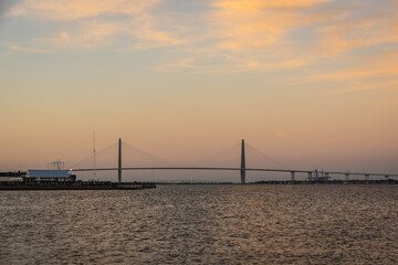 Fototapeta na wymiar A distant bridge over a large body of water at sunset with