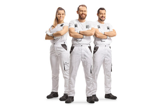 Team of house painters in white overall pants smiling at camera