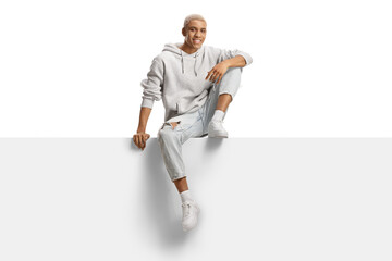 Young african american male with bleached hair sitting on a blank panel