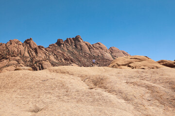 Fototapeta na wymiar Woman looking up at imposing rock mountain in Spitzkoppe Namibia