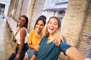 Three cheerful girls friends in summer clothes taking a selfie outdoors at the touristic urban center city. High quality photo
