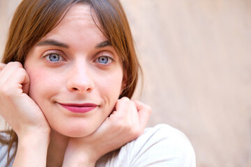 portrait of pretty young girl with blue eyes with hands resting on chin with defocused background