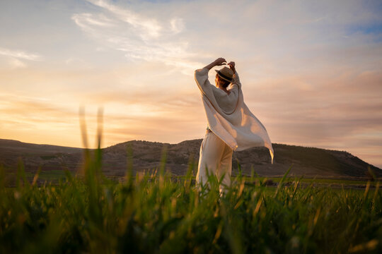 woman wearing a hat in a paceful field at sunset