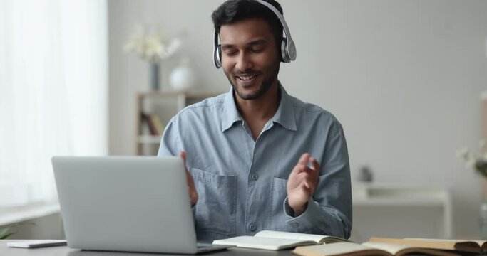 Smiling Indian guy take part in online class, talk to on-line teacher, improve foreign language knowledge remotely using laptop and video call app. Education, e-learning process with Generative AI