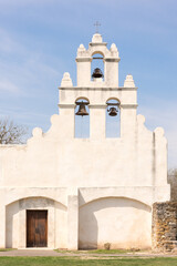 Obraz premium The white adobe Mission of San Juan, bell tower, cross, and wooden entrance door