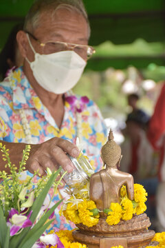 Senior people bathing the Buddha statue and sacred things in the house During Songkran day.