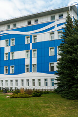 A modern multi-storey office building of unusual shape and coloring. The facade of the building is painted in blue and white.
