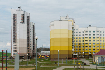 Modern well-maintained residential area with tall multi-colored houses. A new sidewalk and a playground in the courtyard of the house. Lending to the population and renting housing