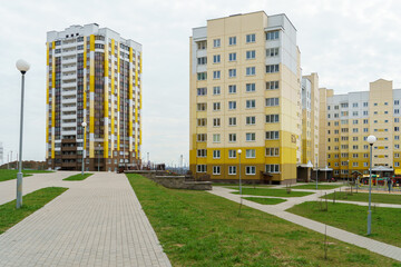 Modern well-maintained residential area with tall multi-colored houses. A new sidewalk and a playground in the courtyard of the house. Lending to the population and renting housing