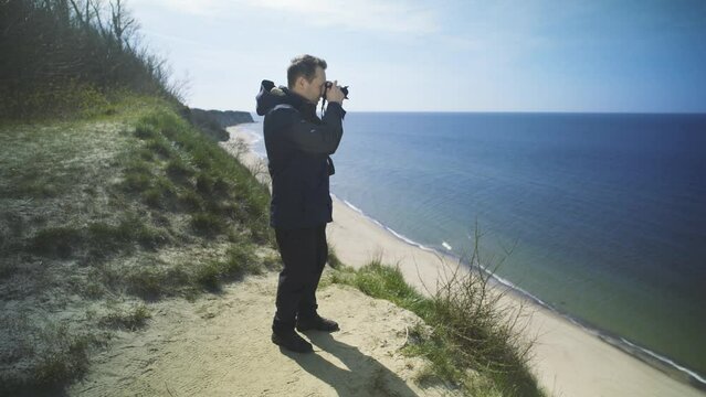 Photographer takes pictures on a cliff by the sea.