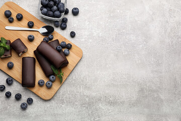 Delicious glazed curd snacks with fresh blueberries and mint on light grey table, flat lay. Space...