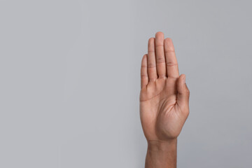 Man giving high five on grey background, closeup of hand. Space for text