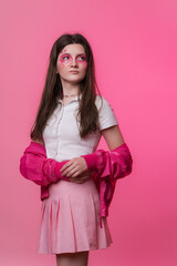 Hipster female with pink stage make-up painted on face, dressed in pink jacket, skirt and white t-shirt. Studio shot of twenty-two-year-old informal woman on colored background. Part of photo series