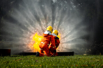 Obraz premium Firefighter Concept. Fireman using water and extinguisher to fighting with fire flame. firefighters fighting a fire with a hose and water during a firefighting training exercise