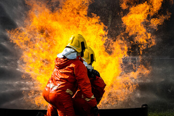 Firefighter Concept. Fireman using water and extinguisher to fighting with fire flame. firefighters fighting a fire with a hose and water during a firefighting training exercise