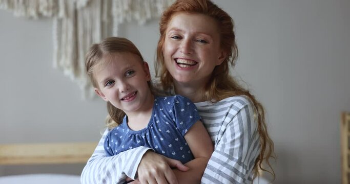 Cheerful red haired young mom cuddling, tickling cute little daughter kid, hugging, holding child in arms, looking at camera, smiling, laughing, enjoying family leisure, motherhood Generative AI