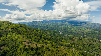 Aerial drone of river in a mountain valley among agricultural land and rice fields. Negros, Philippines