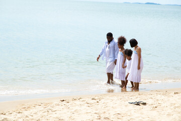 Fototapeta na wymiar Black family having fun on the beach. mixed race family relaxing at the beach on summer holiday