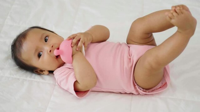 infant baby biting mushroom teether rubber toy on a bed