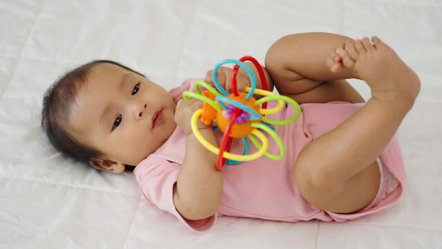 infant baby biting colorful rubber bites toy on a bed