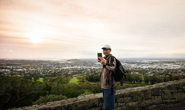 Tourist taking selfie photos with smartphone at One Tree hill. Auckland.