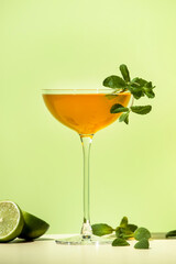 Old Cuban alcoholic cocktail drink with white rum, lime juice, sparkling wine, syrup, bitter, mint and ice. Lime green background, hard light, shadow pattern