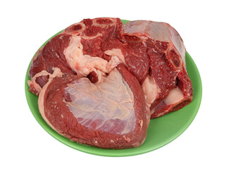 A large piece of raw beef with bones and ribs on a green plate isolated