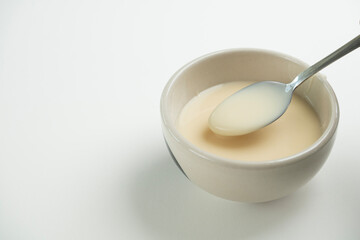 Fototapeta na wymiar close up of condensed milk with spoon isolated on white background, food ingredients concept