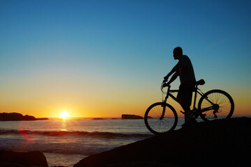 Fototapeta na wymiar Man, beach and silhouette with mountain bike, sunset and mockup space by waves for summer cycling adventure. Cyclist, freedom and fitness with bicycle, training or journey by ocean in dusk sunshine