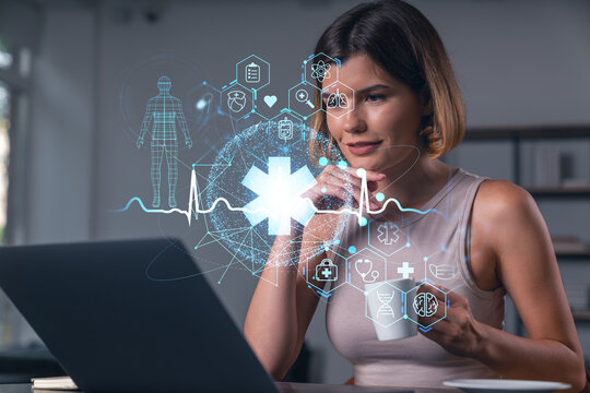 Thoughtful businesswoman in casual wear typing on laptop at office workplace with coffee cup. Concept of distant work, business, internet surfing, information technology. Medical icons hologram