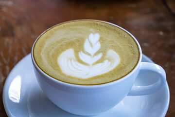 Green tea latte in white cup on wooden desk