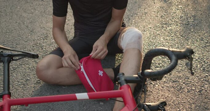 sportsman sitting on the road with injured leg holding first aid kit, looking for pills to relief pain dangerous sport Medicine , treatment concept