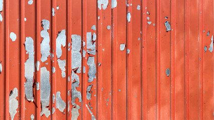 Red striped galvanized corrugated roofing sheet with peeling paint. The texture is made of old silver steel corrugated iron with a red beauty that has come down.