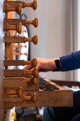 Organist playing a church organ. Seen from the side, narrow depth of field, focus on the wooden...